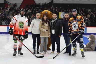 six personnes, une mascotte en forme de castor et des peluches sur une patinoire