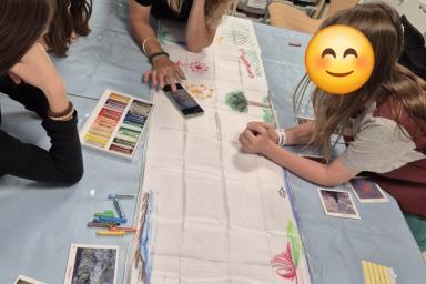 trois enfants dessinent sur une écharpe accompagné d'une médiatrice