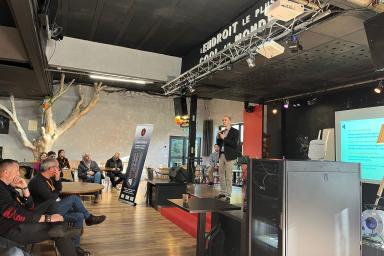 Photo d'une personne avec un micro sur une estrade devant un public