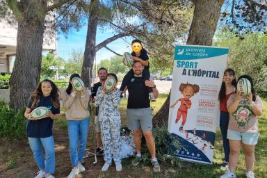 Des enfants hospitalisés posent pour une photo de groupe aux côtés de 2 entraîneurs du Rugby Club Les Angles Gard Rhodanien venus spécialement dans le cadre d'une activité sportive organisée en partenariat avec l'association Premiers de Cordée