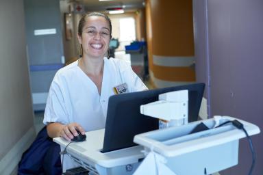 Gros plan sur une soignante très souriante devant son ordinateur - Agrandir l'image, fenêtre modale