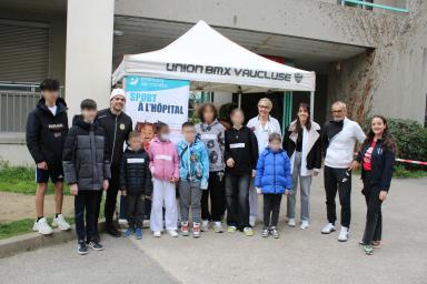 Des enfants et adultes posent devant un kakémono et une tente de reception