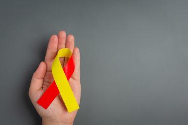Ruban rouge et jaune représentant la sensibilisation à l'hépatite posé dans une main