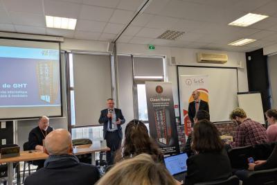 Photo d'une personne avec un micro sur une estrade devant un public - Agrandir l'image 1 sur 3, fenêtre modale