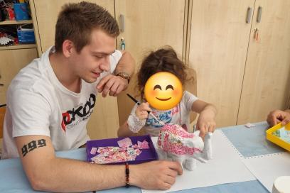 Un bénévole de l'Association Cékedubonheur aide un enfant hospitalisé à créer un éléphant avec la méthode déco patch lors d'un atelier créatif - Agrandir l'image, fenêtre modale