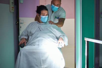 Gros plan sur un soignant qui pousse une patiente sur le point d'accoucher en fauteuil roulant - Agrandir l'image, fenêtre modale