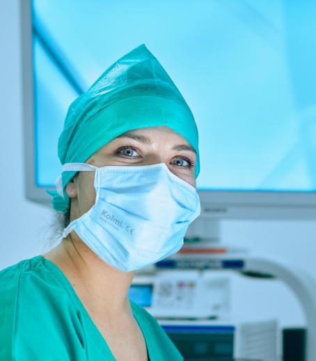 Une agente hospitalière du bloc opératoire en tenue regarde l'objectif en souriant