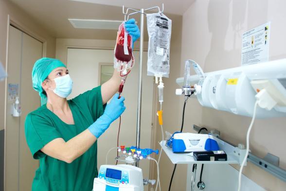 Gros plan sur une soignante qui manipule une poche de sang - Agrandir l'image, fenêtre modale