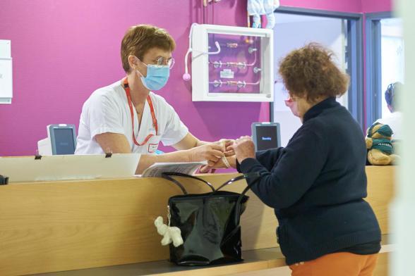 Une soignante met un bracelet d'identification à une patiente - Agrandir l'image, fenêtre modale