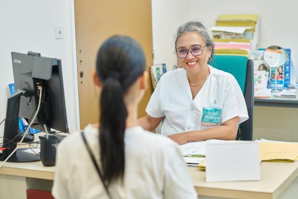 Une infirmière reçoit une patiente dans un bureau et discute avec elle en souriant - Agrandir l'image, fenêtre modale