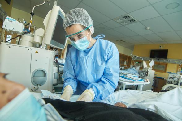 Une soignante s'occupe d'un patient dans une chambre - Agrandir l'image, fenêtre modale