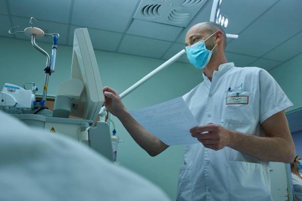 Un infirmier tient une fiche médicale et renseigne des données dans un ordinateur - Agrandir l'image, fenêtre modale