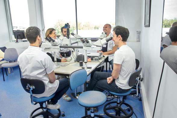 Des techniciens de laboratoire souriants font des analyses au microscope - Agrandir l'image, fenêtre modale