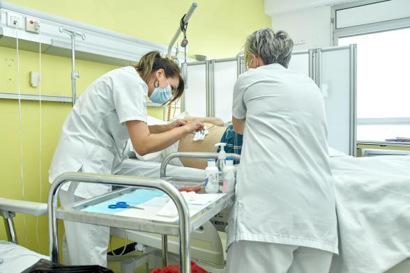 Deux soignantes s'occupent d'un patient - Agrandir l'image, fenêtre modale