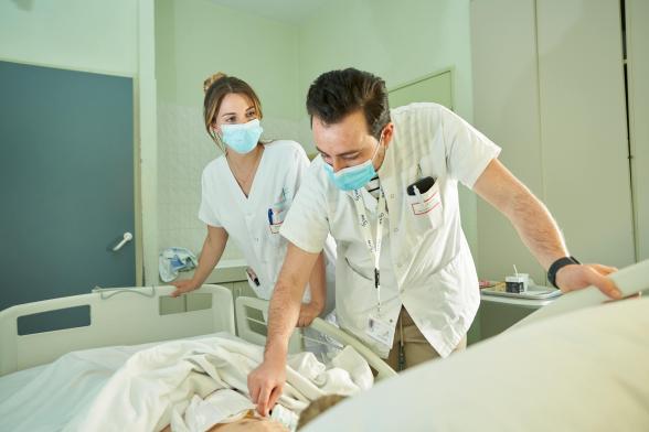 Gros plan sur deux soignants dans une chambre auscultant un enfant - Agrandir l'image, fenêtre modale