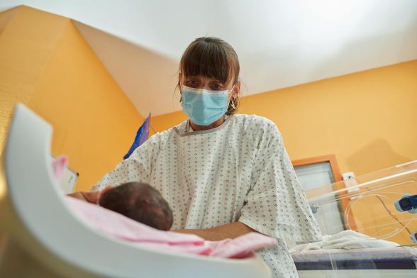 Gros plan sur une soignante s'occupant d'un nourrisson - Agrandir l'image, fenêtre modale