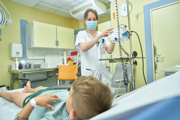 Une soignante s'occupe d'un jeune patient dans une chambre - Agrandir l'image, fenêtre modale