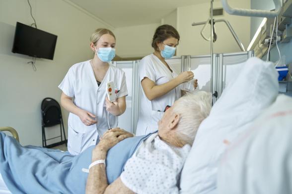 Deux soignantes s'occupent d'un patient - Agrandir l'image, fenêtre modale