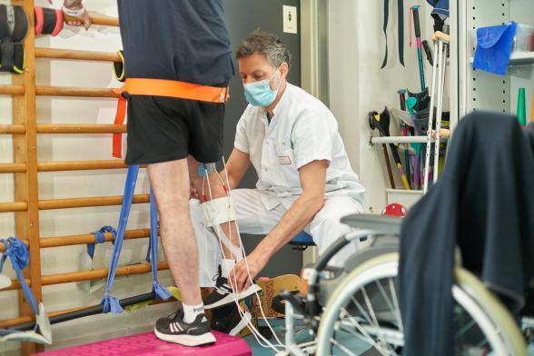 Un soignant aide à la rééducation de la jambe d'un patient - Agrandir l'image, fenêtre modale