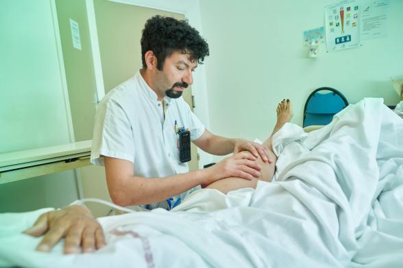 Un soignant s'occupe d'une patiente dans un lit - Agrandir l'image, fenêtre modale