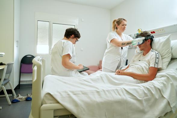 Deux infirmières installent un casque de réalité virtuelle sur la tête d'un patient - Agrandir l'image, fenêtre modale