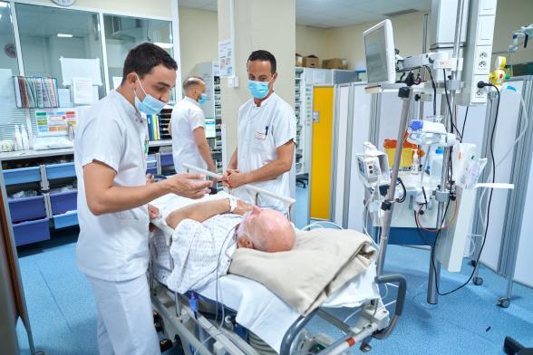 Des soignants discutent avec un patient dans un brancard - Agrandir l'image, fenêtre modale