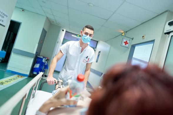 Un soignant pousse un brancard - Agrandir l'image, fenêtre modale