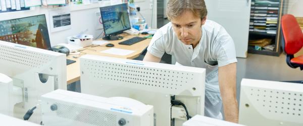 Gros plan sur un soignant renseignant des éléments sur un ordinateur 