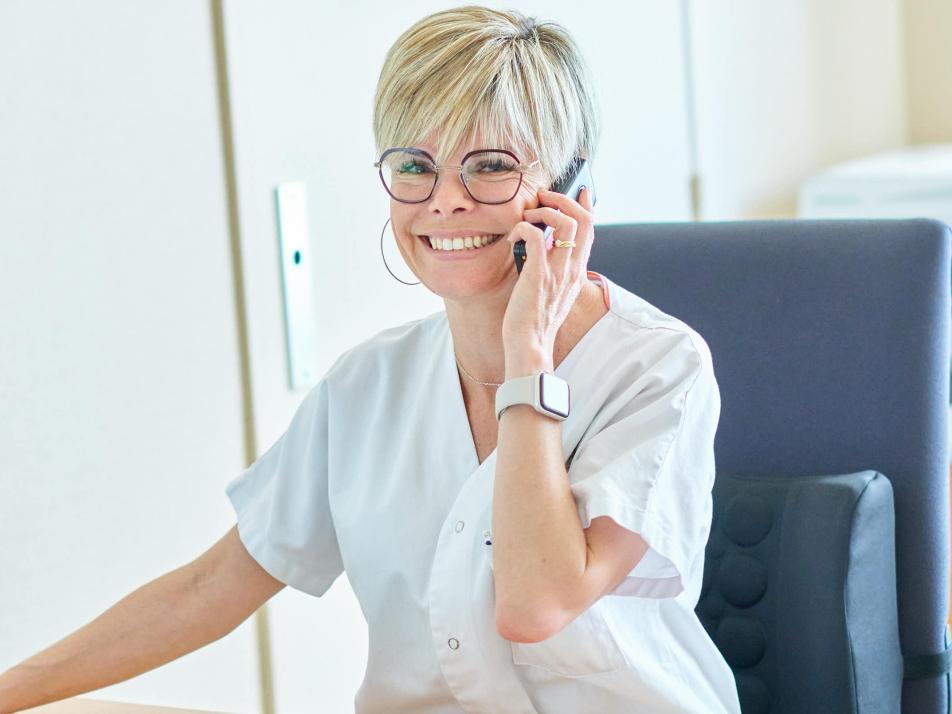 Gros plan sur une soignante souriante au téléphone