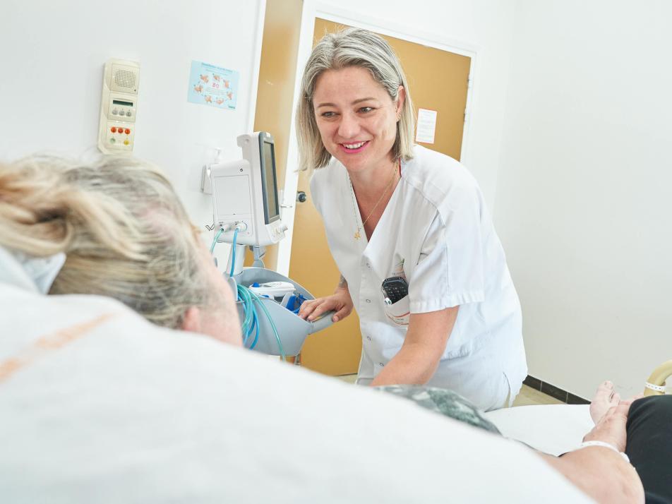Une soignante souriante discute avec une patiente dans une chambre